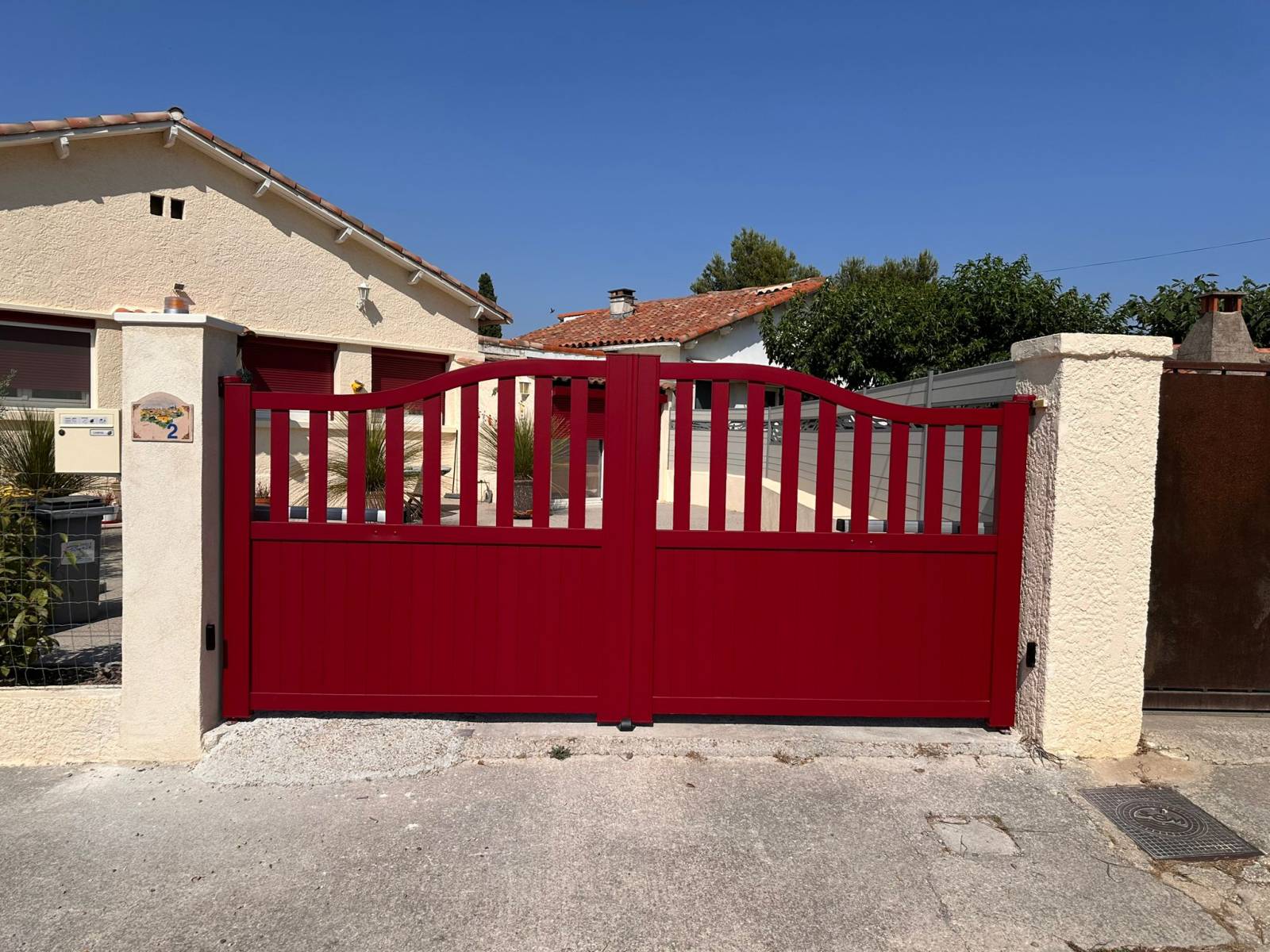 Un portail à double battant en aluminium rouge motorisé, modèle Authentique, pour une entrée de caractère à Aix-en-Provence
